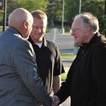 Two attendees shake hands while another looks on