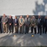 Black plane team members stand in front of the addition to the monument.