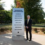 Mike Bruce stands by the survivor's monument