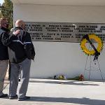 Two men stand in front of the memorial, one has his hand on the other's back