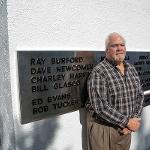 A man stands beside his name on the black plane addition to the monument