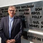 John Yeros stands beside his name on the black plane addition to the monument