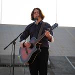 A student vocalist sings "Where Have All the Flowers Gone?" on guitar, shot vertically