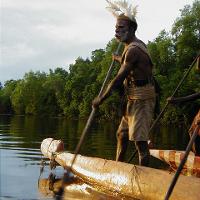 An Asmat man rows a boat on a river