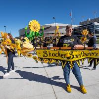 Shocker Sunflowers show off their banner as they begin the parade with several sunflowers and students in the back. 