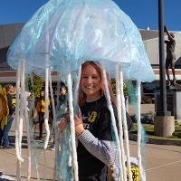 Woman holds iridescent blue jellyfish costume for the parade.