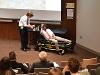 Zachary affixes the team's prototype restraint to Faizan to demonstrate its compatibility with a stretcher. 