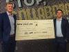 Jon and Jacob hold the giant $10,000 check in front of the mural in the Widget room at Devlin Hall.