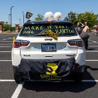 The back of one of the vehicles in the cruise. There is a saying on the back windshield along with some balloons and draped cloth.