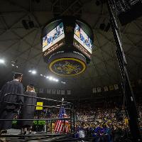 A photo taken of the teleprompter at a low angle. A few graduates waiting to receive their diplomas in the bottom right corner.