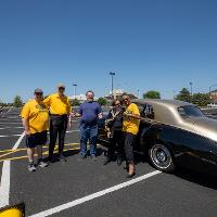 Several participants of the Commencement Cruise standing beside their vehicle before the start of the Cruise.