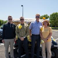 Several people standing beside their decorated golf cart before the cruise started.