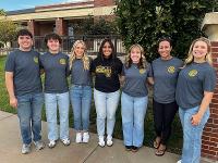 Gore Scholars in heather gray t-shirts pose for a photo outside the Marcus Welcome Center.
