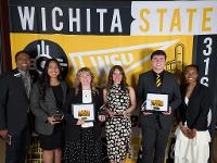 A group of Gore scholars pose in front of a Wichita State backdrop at an awards ceremony.