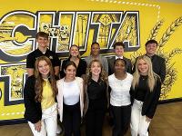 A group of students poses in front of the Wichita State mural inside the Rhatigan Student Center.