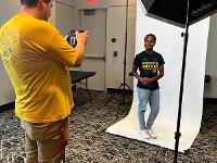A student poses for a photo in a professional photography setup.