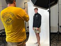 A student poses for a photo in a professional photography setup.