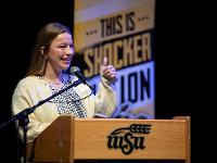One Gore Scholar stands at a podium to speak to the audience.