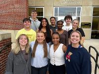 A group of students pose for a photo in front of the Marcus Welcome Center.