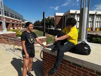 Two students chat outside the Rhatigan Student Center's east entrance.