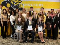 A group of students and alumni pose for a photo in business dress apparel.