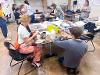 Two instructors assemble collages at a table filled with craft materials.
