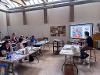 Instructors seated facing a screen with multicolored, abstract artworks projected onto it.