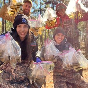  four students hold bagged specimens in camo bibs