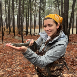 Girl in camo bibs holding snake