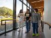 Students walk up the back entrance ramp to the Shocker Success Center. Ablah Library can be seen through the window in the background.