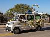 Students drive in a van with "Housing and Residence Life" and "WSU" written on with with yellow, black and white ribbons strung around it. A student lays on top of the van holding up black, yellow and white ribbons.