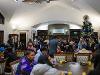 Students gather indoors at the Winter Welcome at the President's Residence. Holiday decorations fill the room, including trees and lights.