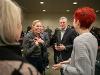 Dr. Monica Lounsbery, left, laughs while speaking with Wichita State University President Rick Muma and College of Fine Arts Dean Marie Bukowski during a campus reception. The group stands in a crowded room filled with faculty and staff.
