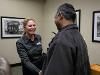 Dr. Monica Lounsbery, senior executive vice president and provost at Wichita State University, smiles while shaking hands with an attendee during a reception. They are standing in a room with framed black-and-white photographs on the wall.