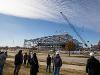 A group of people wearing hard hats watch as a crane lifts the final steel beam into place atop the Hub for Advanced Manufacturing and Research on Wichita State’s Innovation Campus