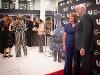 People in formal attire gather at the Ulrich Museum of Art during the Ulrich50 Gala. Some guests are chatting near a bar area, while others pose on a red carpet in front of a backdrop with the museum’s logo.
