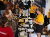 Employees from Wichita State University staff a booth at the Kansas State Fair. Attendees visiting are taking a variety of goods and swag from the booth.