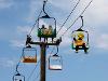 WuShock catches a ride on a gondola lift at the Kansas State Fair and waves at attendees passing by on another gondola lift.