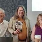 Alumnus Seth Bate, center, celebrates the release of his award-winning book on the Walnut Valley Festival at Watermark Books.