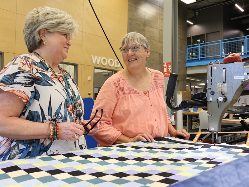 two happy women working at quilt machine