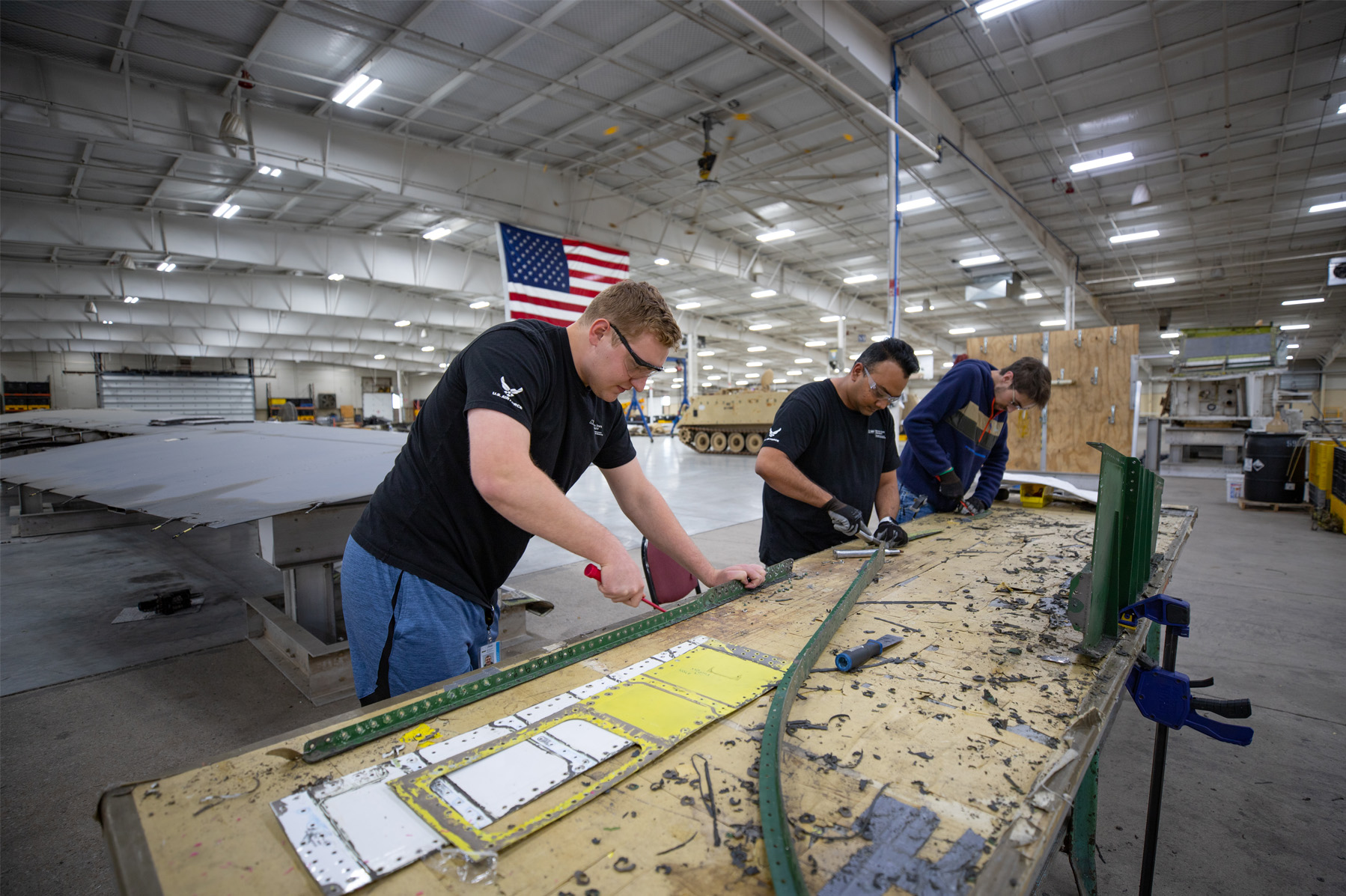 Three NIAR employees working at a table on an airplane part in the sustainment lab