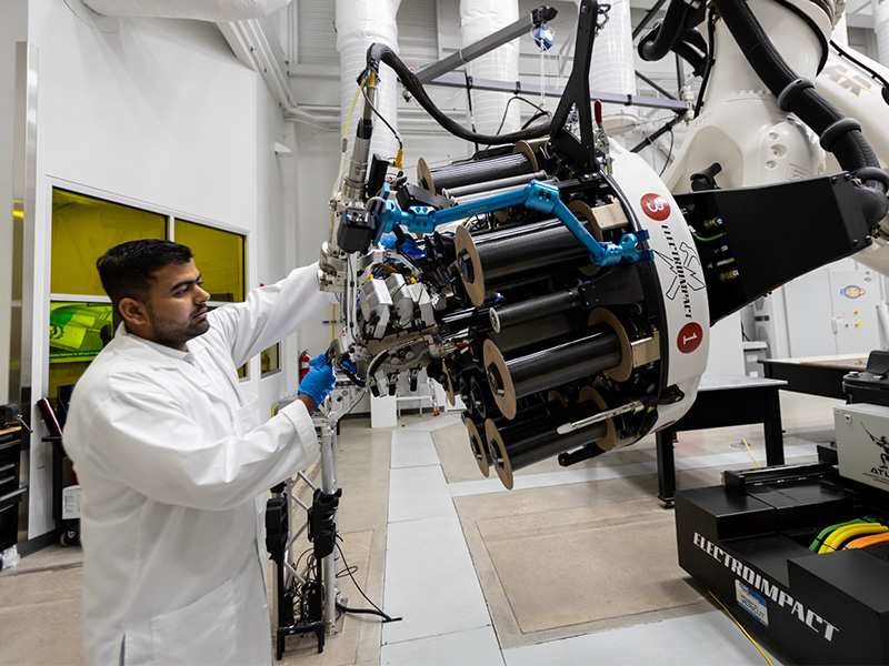 Employee working on a piece of equipment and loading material onto the machinery.
