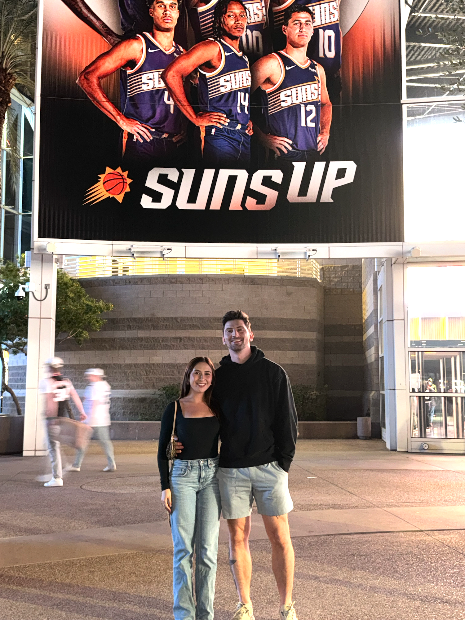 Andrew Gross and one other in front of a basketball poster