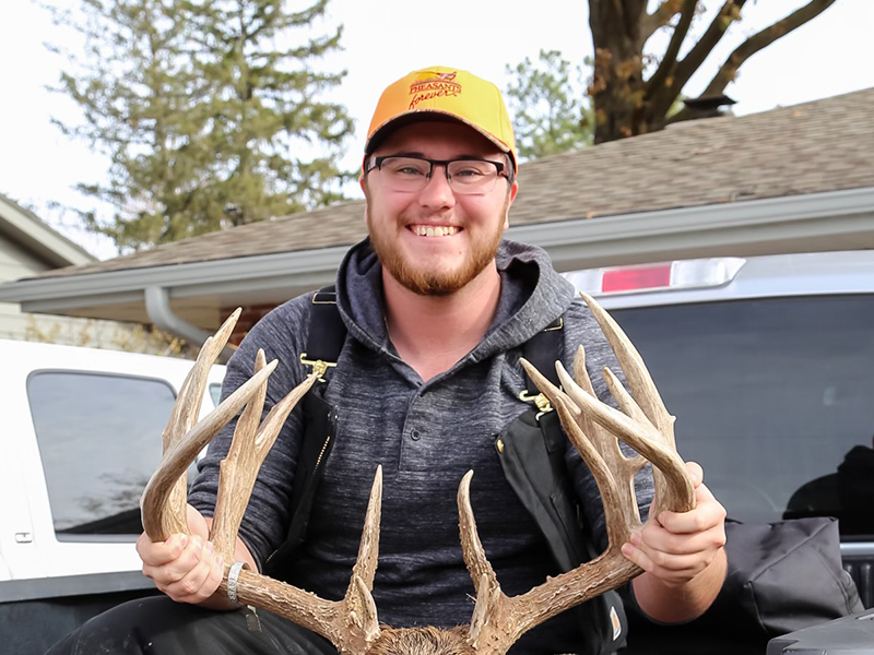 Photo pf Regan Archibald in hunting gear with a deer