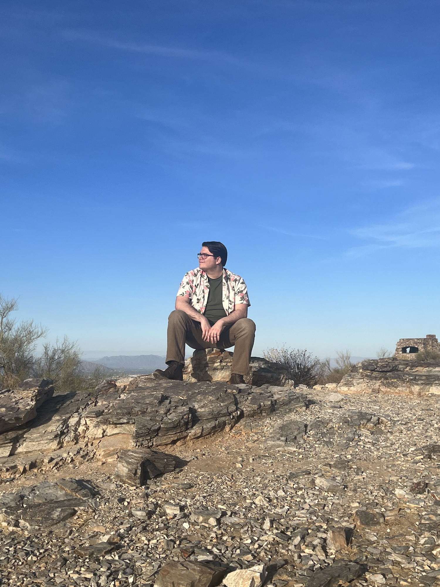 Photo of Nathaniel Wheatley sitting on a mountain top in the desert.