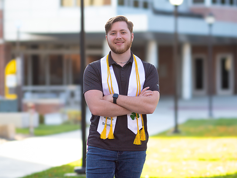 Photo of Alex Harms wearing their graduation stole.