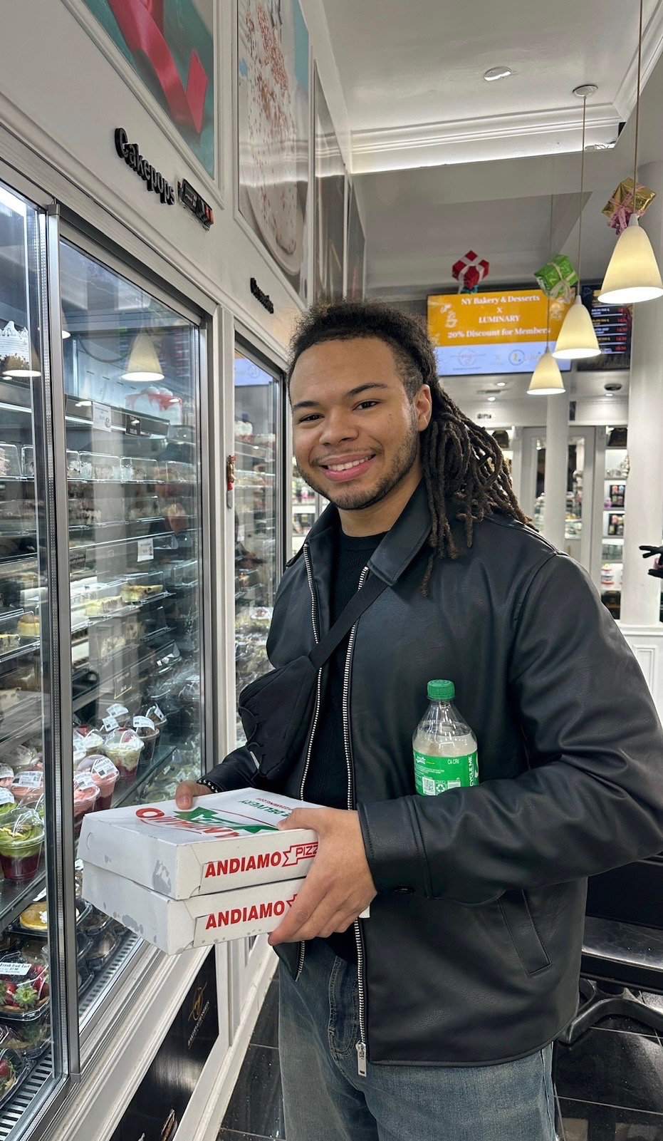 Photo of Cameron Davis in a bakery, holding pizza boxes.