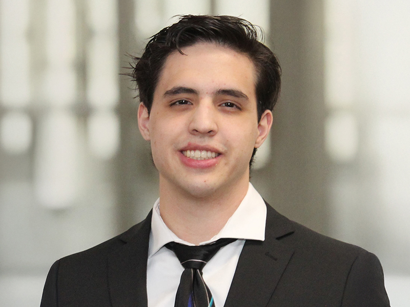 Photo of Justen Lee wearing a suit and tie.