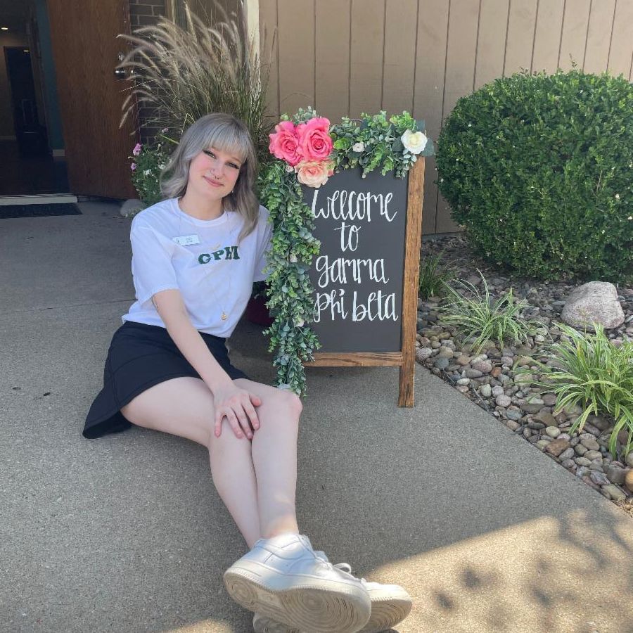 Photo of Emily Evans in front of a gamma phi beta sign