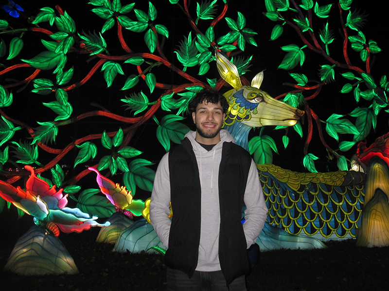 Photo of Alaa Qaki in front of a light sculpture